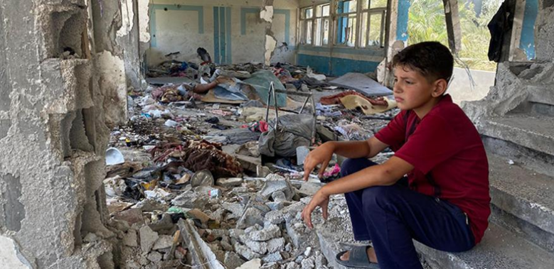 Boy sits in rubble in Gaza