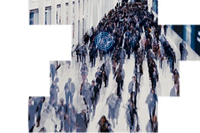 Business people moving at pace inside a modern complex with digital advertising screens on either side of a wide walkway